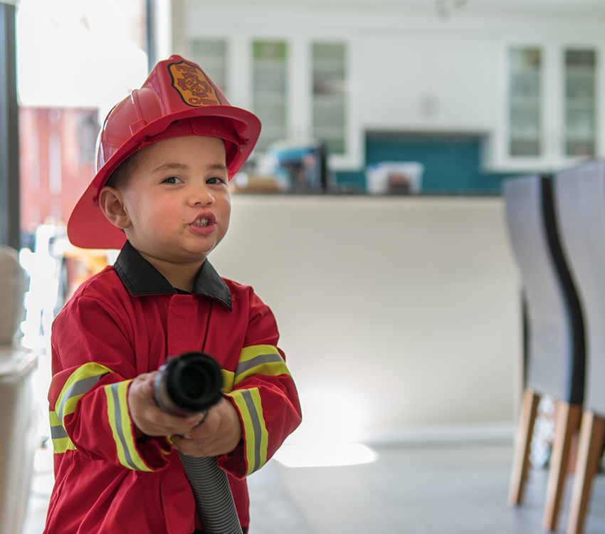 Παιδί με στολή πυροσβέστη που κρατάει πυροσβεστήρα